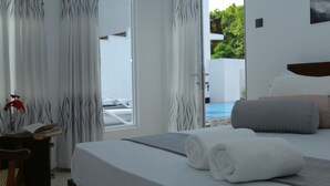 Habitació d'hotel amb un llit, vista a una piscina i una porta que dóna a l'exterior.