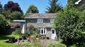 A stone house with a garden, a chimney, and a small porch. - Gwardolau Cottage, Wye Valley Retreat. (Rhayader)
