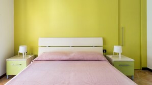 Un lit avec une tête de lit blanche, deux tables de chevet avec des lampes et un mur vert.