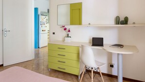Une chambre moderne équipée d’un bureau, d’une chaise et d’une petite étagère agrémentée d’objets décoratifs.