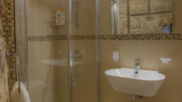 Un baño con cabina de ducha de vidrio, lavamanos y espejo.