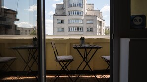 Un balcón con dos sillas y una mesa, con vistas a un edificio con múltiples ventanas y balcones.