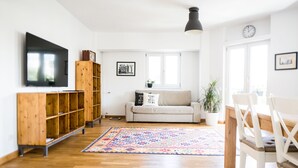 Amplia sala de estar con mueble de madera para entretenimiento, un sofá, una mesa de centro y un comedor con sillas.