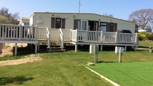 A mobile home with a deck and a fenced area.