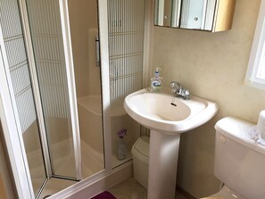 A bathroom with a glass shower enclosure, a pedestal sink, and a toilet. - Enjoy a break in our dog friendly, chalet style, static van with ferry discounts (St. Helens, Isle of Wight)