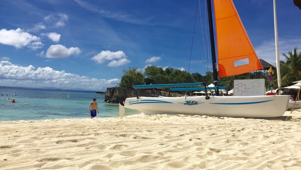 A sandy beach with a sailboat docked near the shore.