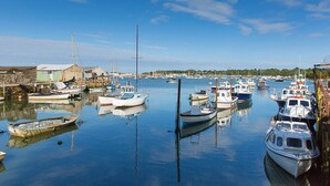 A marina with various boats docked, calm water, and a clear sky.