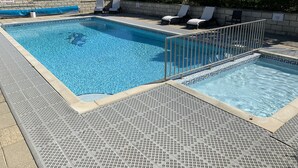 A rectangular swimming pool with a safety rescue pole, lounge chairs, and a depth sign.