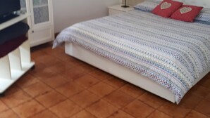 Un dormitori amb un llit, una televisió, un armari i un quadre a la paret.