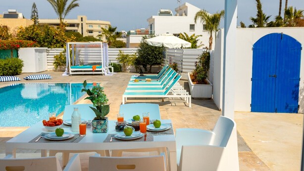 A poolside dining area with tables, chairs, and lounge chairs. - This amazing luxury villa is located in the heart of Protaras just 4 minutes walk to the Main Str (Protaras)