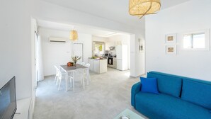 A modern living room with a blue sofa, a dining area with white chairs, and a kitchen in the background. - This amazing luxury villa is located in the heart of Protaras just 4 minutes walk to the Main Str (Protaras)