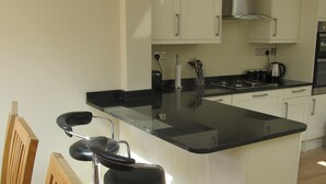 A modern kitchen with white cabinets, a black countertop, and stainless steel appliances. - Chloe Cottage - Family friendly fishermans cottage close to the beach and harbou (Whitstable)