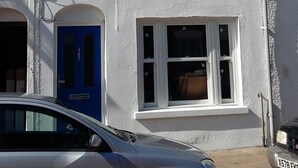 A two-story building with white walls and multiple windows. There is a blue door on the ground floor. - Chloe Cottage - Family friendly fishermans cottage close to the beach and harbou (Whitstable)