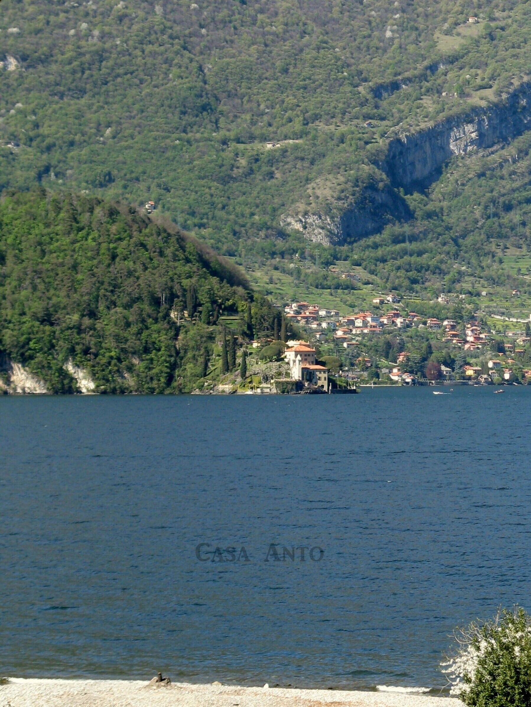 A lake with a small village on the shore, surrounded by forested hills.