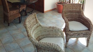 Un espace extérieur aménagé avec des meubles en osier, une table et une plante en pot.