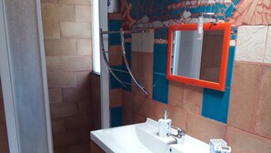 Une salle de bain avec une douche, un lavabo avec un miroir et des toilettes.