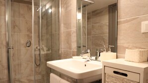 A modern bathroom with a glass-enclosed shower, a double sink vanity, and a large mirror.