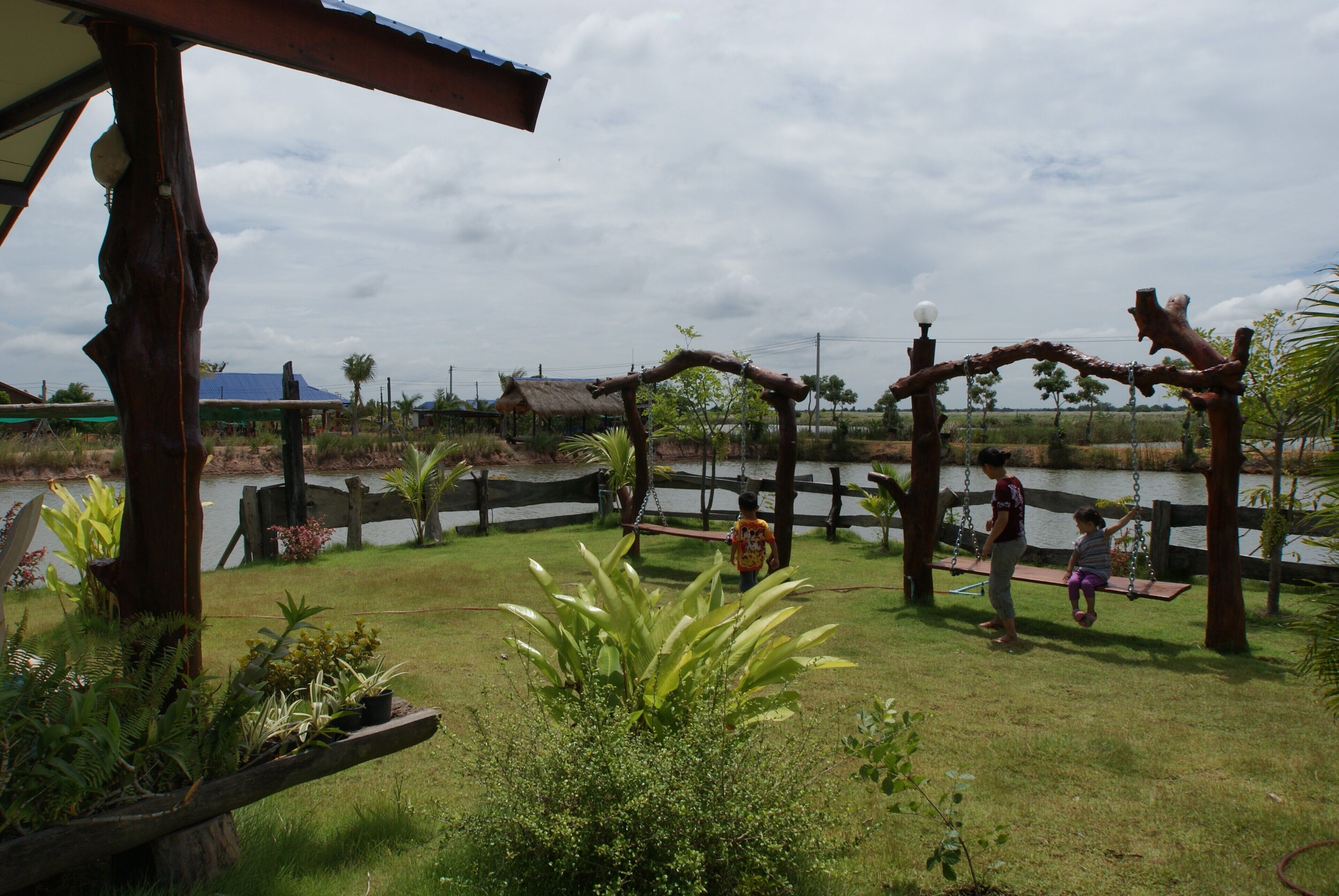 A wooden swing set over a grassy area with a pond in the background.