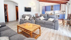 Una sala de estar con dos sofás grises, una mesa de centro de madera y un televisor montado en la pared.
