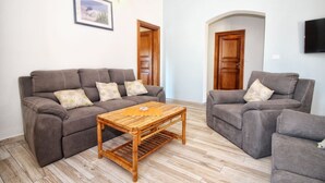 Una sala de estar con dos sofás grises, una mesa de centro de madera y un cuadro enmarcado en la pared.