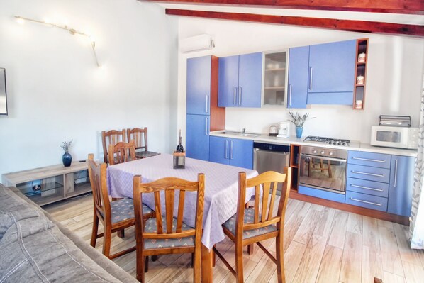 Une cuisine compacte avec des meubles de rangement bleus, une table à manger avec des chaises et un petit coin repas.