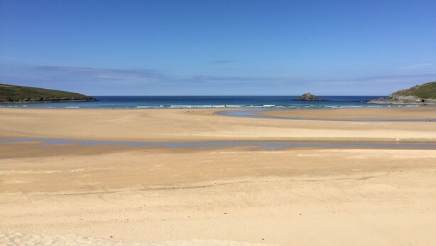 A wide sandy beach with gentle waves, a clear blue sky, and a small rocky outcrop in the distance. - Clemens Beach House, Sea Views, Private Lane, Crantock, Sleeps 4. (Crantock, Cornwall)