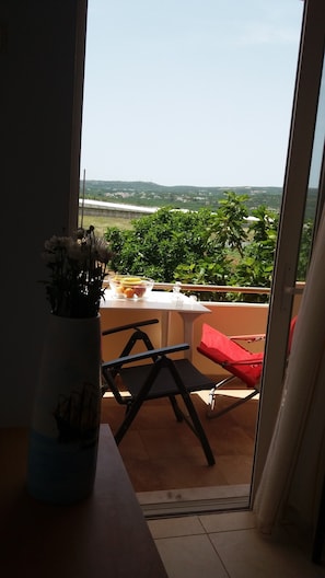 Un balcon avec une table, des chaises et un vase de fleurs.