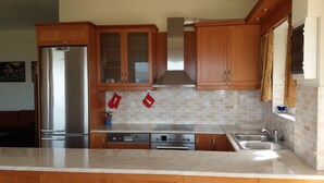 A modern kitchen with wooden cabinets, stainless steel appliances, and a tiled backsplash.