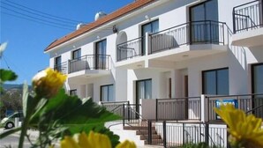 Un edificio residencial de varios pisos con balcones, ventanas amplias y cielo despejado.