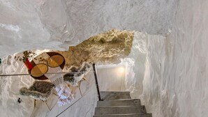 Un escalier à l’intérieur d’une structure ressemblant à une grotte, avec une échelle en bois et une rambarde en corde.
