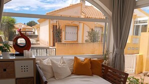 Ein Schlafzimmer mit Bett, Kissen, einem Nachttisch und Blick ins Freie.
