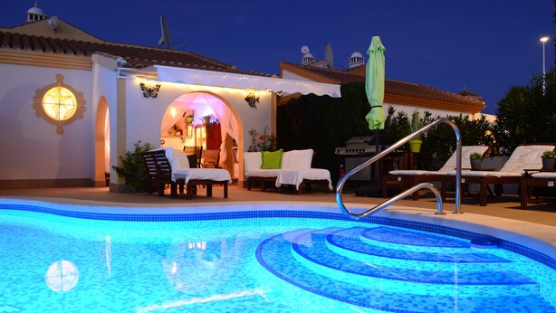 Ein Pool mit einer Vertiefung in der Mitte, Liegestühlen und einer überdachten Sitzgruppe mit Tisch und Stühlen.
