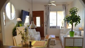 Ein Wohnzimmer mit Sofa, Couchtisch, Esstisch und einer Zimmerpflanze.