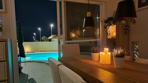 Ein Essbereich mit Blick auf einen Swimmingpool in der Nacht.
