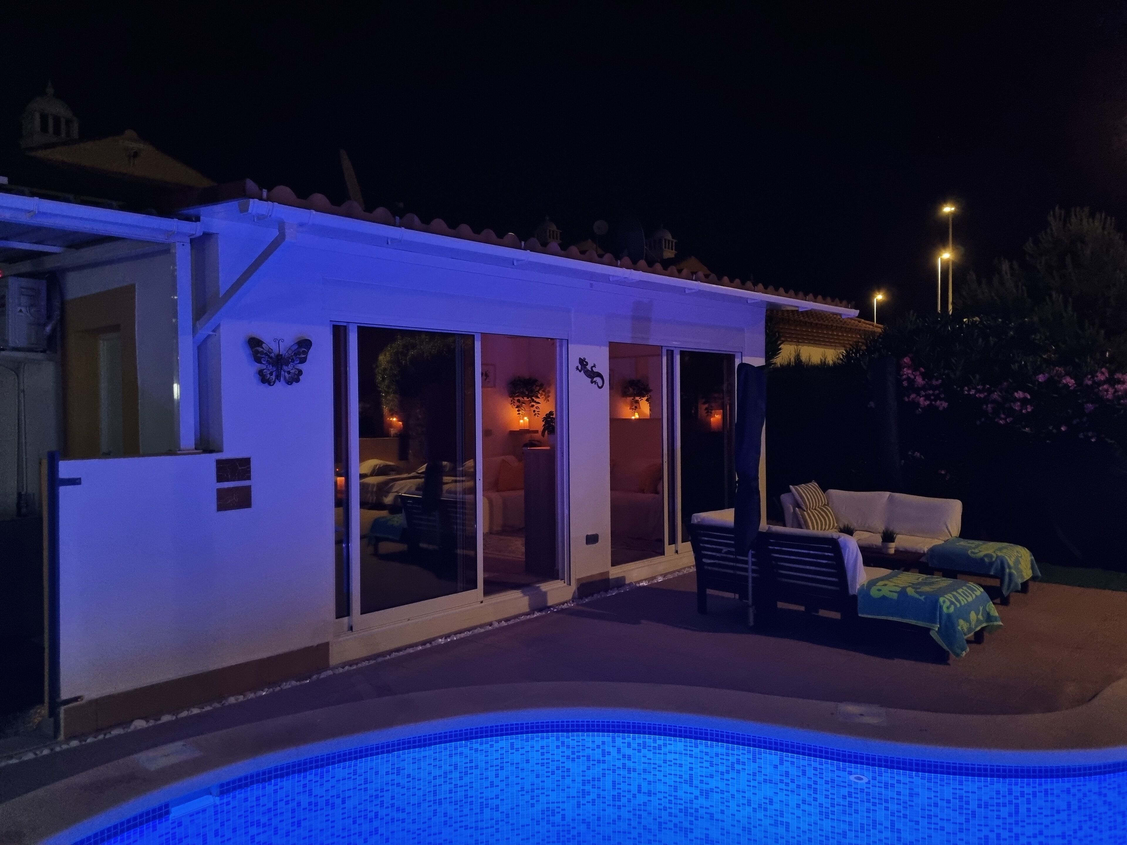 A poolside area with a covered patio, a pool, and a view of a building with a dome in the background.