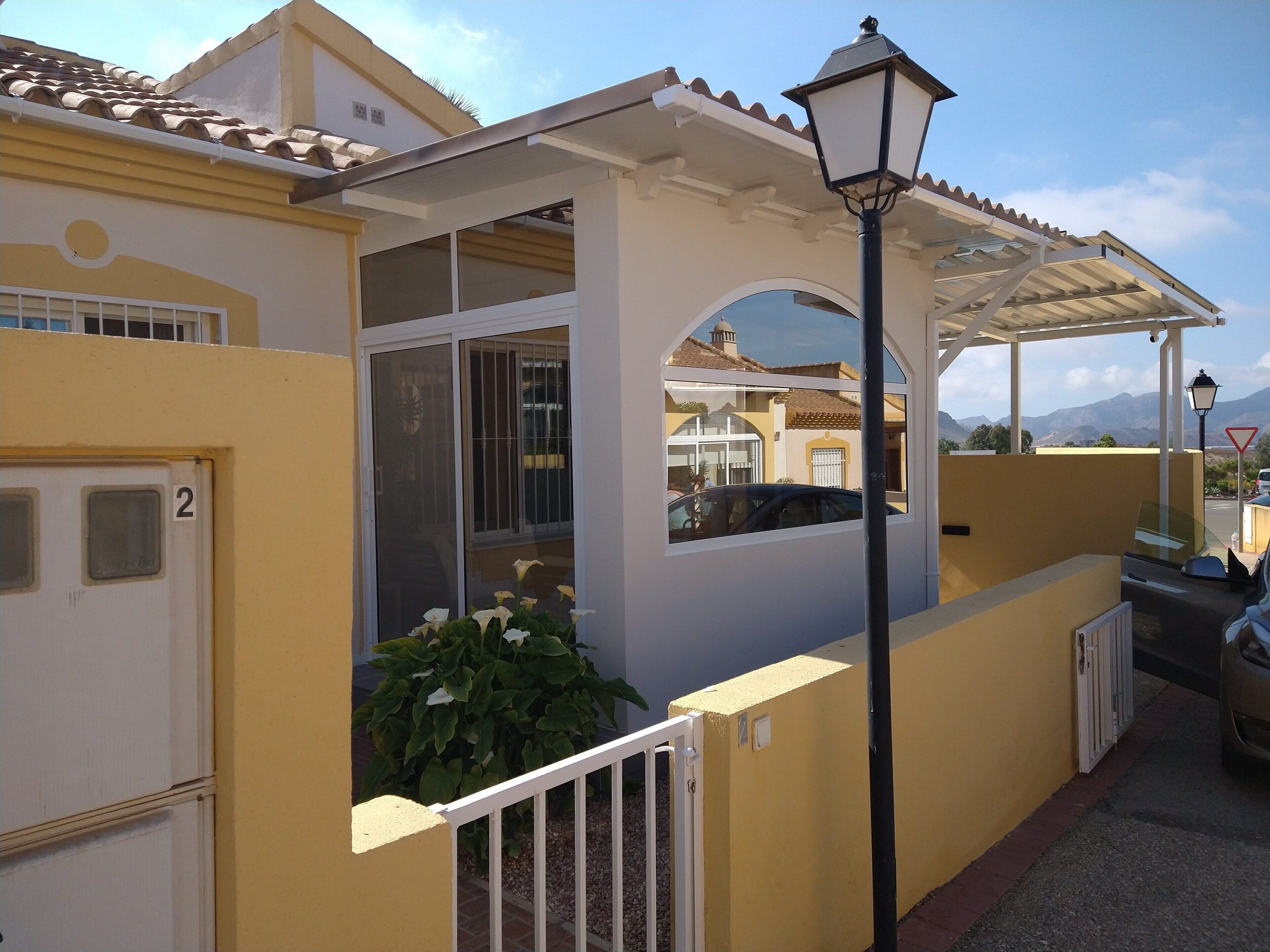A yellow building with a white door marked with the number 2, a covered porch, and a street lamp.