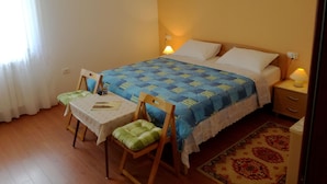 A small, neatly arranged bedroom with a single bed, a bedside table, a chair, and a table.