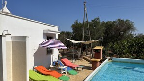Une piscine avec des chaises longues et un espace patio couvert.