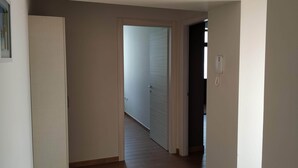 A narrow hallway with wooden flooring, a white door on the left, and a door leading to another room on the right. - Bice's House - Accommodation 3 (Cassibile)