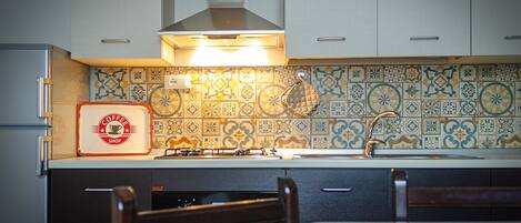 A kitchen with a tiled backsplash, a gas stove, and a coffee shop sign.