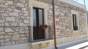 A stone building with a balcony and two windows, each with a flower pot. - Bice's House - Accommodation 3 (Cassibile)