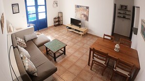 A living room with a sofa, a coffee table, a TV, and a dining table with chairs.