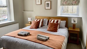 Een slaapkamer met een bed, twee nachtkastjes, een raam en een kunstwerk aan de muur.
