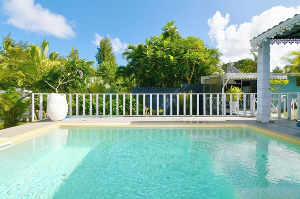 A clear swimming pool with a white fence, surrounded by lush greenery and a gazebo. - Riambel: Villa Antema, pool, right on the beach (Riambel)