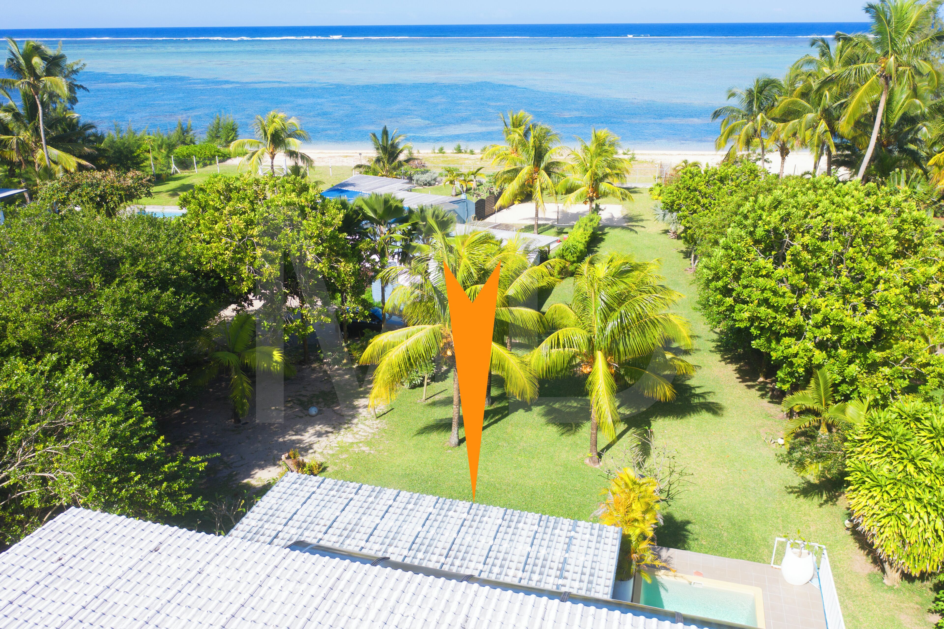 Ein tropisches Resort mit Pool, Palmen und Blick auf den Ozean.