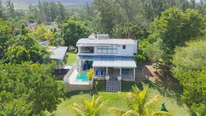 A two-story house with a swimming pool, surrounded by lush greenery and a view of distant mountains. - Riambel: Villa Antema, pool, right on the beach (Riambel)