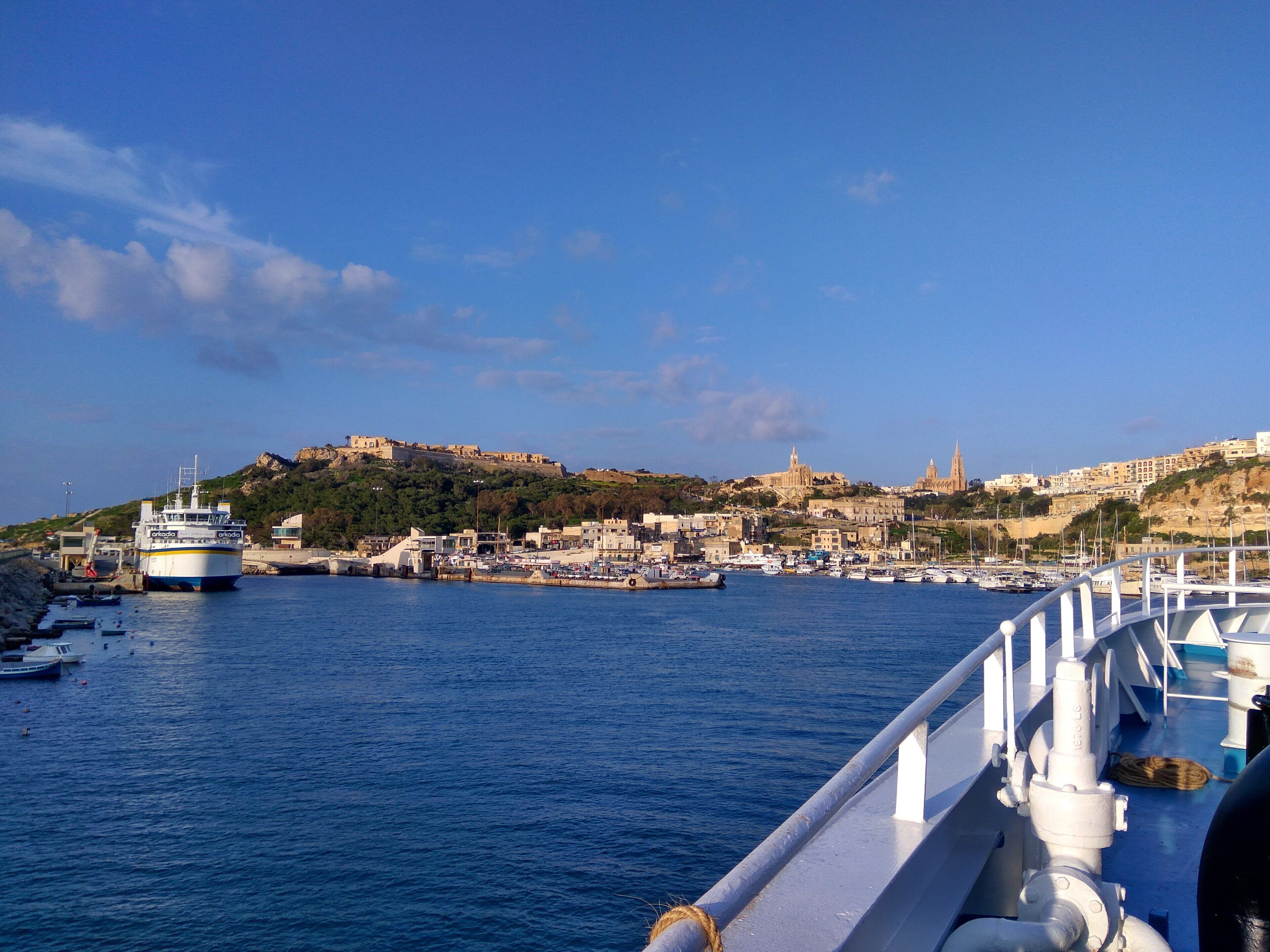 Un port avec des bateaux, un grand navire et un bâtiment historique situé sur une colline.