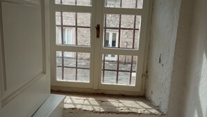 A room with a large window, a white bench, and a view of a stone building outside. - Ivo Apartment  in Dubrovnik Old Town (Dubrovnik)
