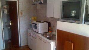 Una cocina compacta con microondas, tostadora y lavamanos.