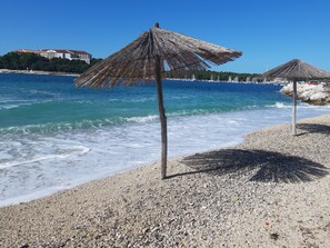 A pebbled beach with thatched umbrellas and a clear blue sea. - Cozy "Saltwater Soul" apartment with a stunning sea view. Nearby the sea. (Pješčana uvala, Pula)
